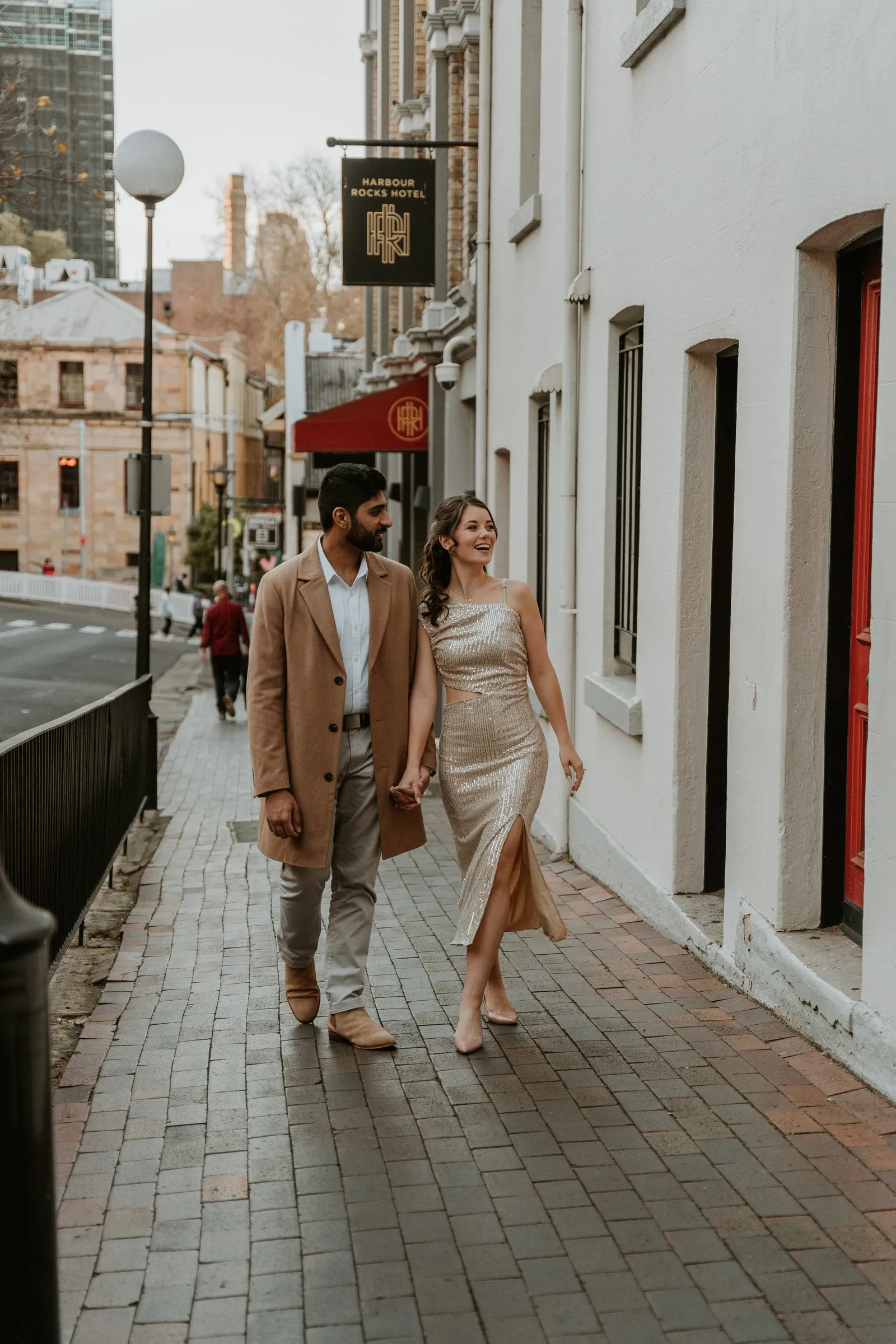 A couple walking hand in hand along a city footpath