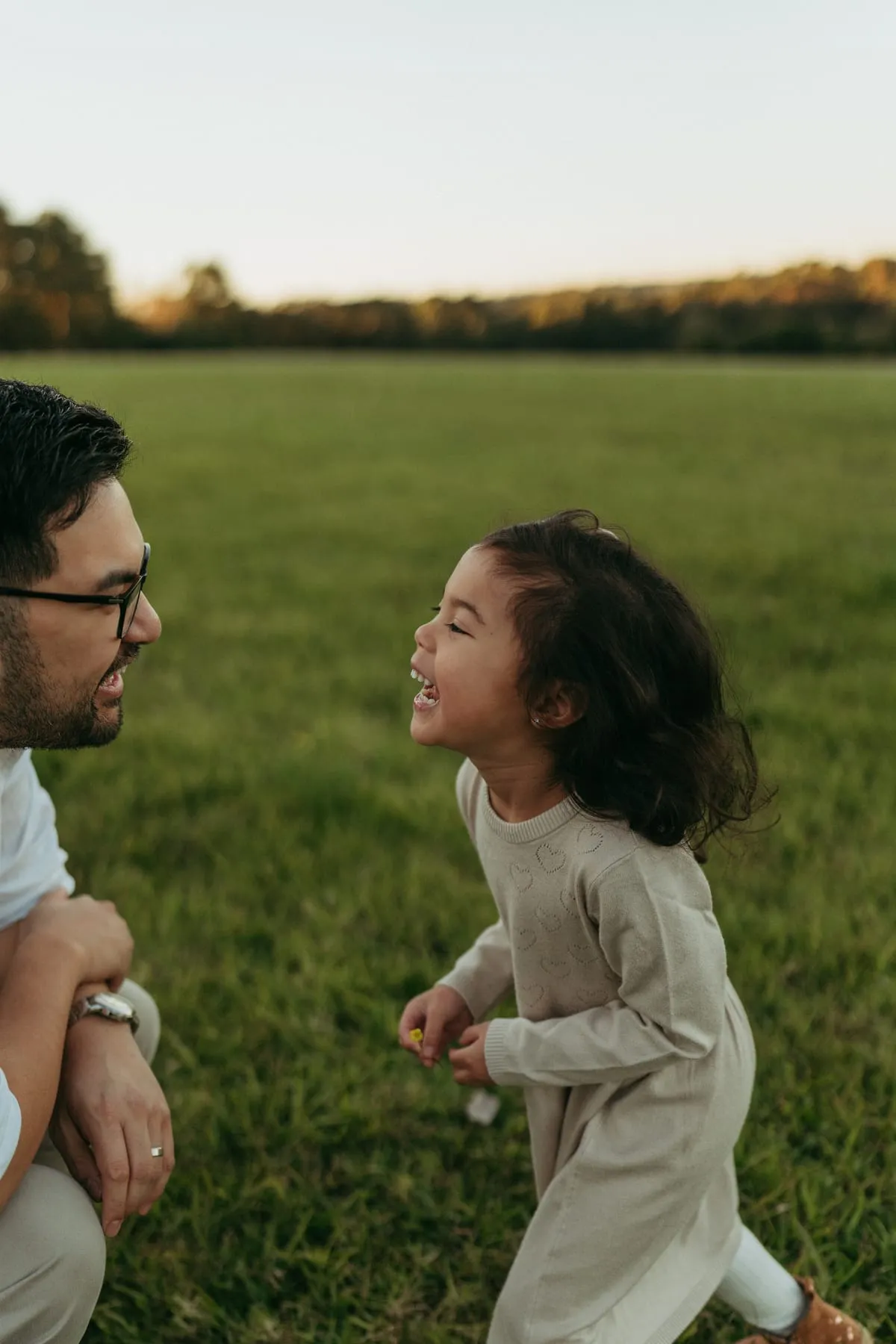 A dad and his daughter grinning at each other