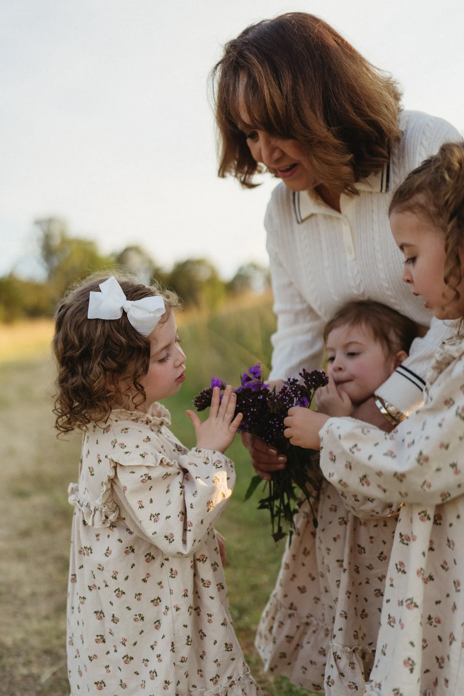 A mum holding her baby while two little girls gather close