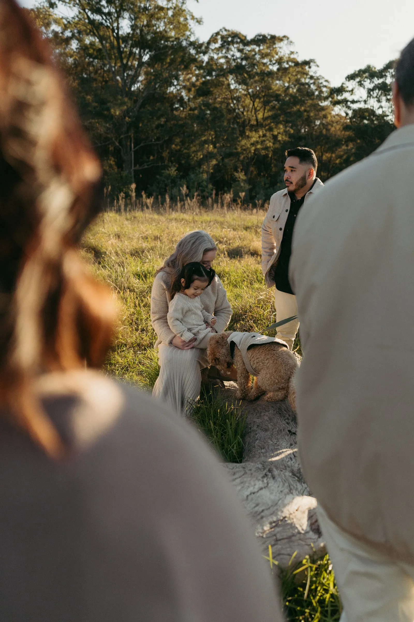 An extended family holding hands in a circle in the grass