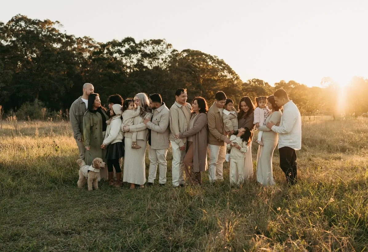 A large extended family gathered in a field at sunset