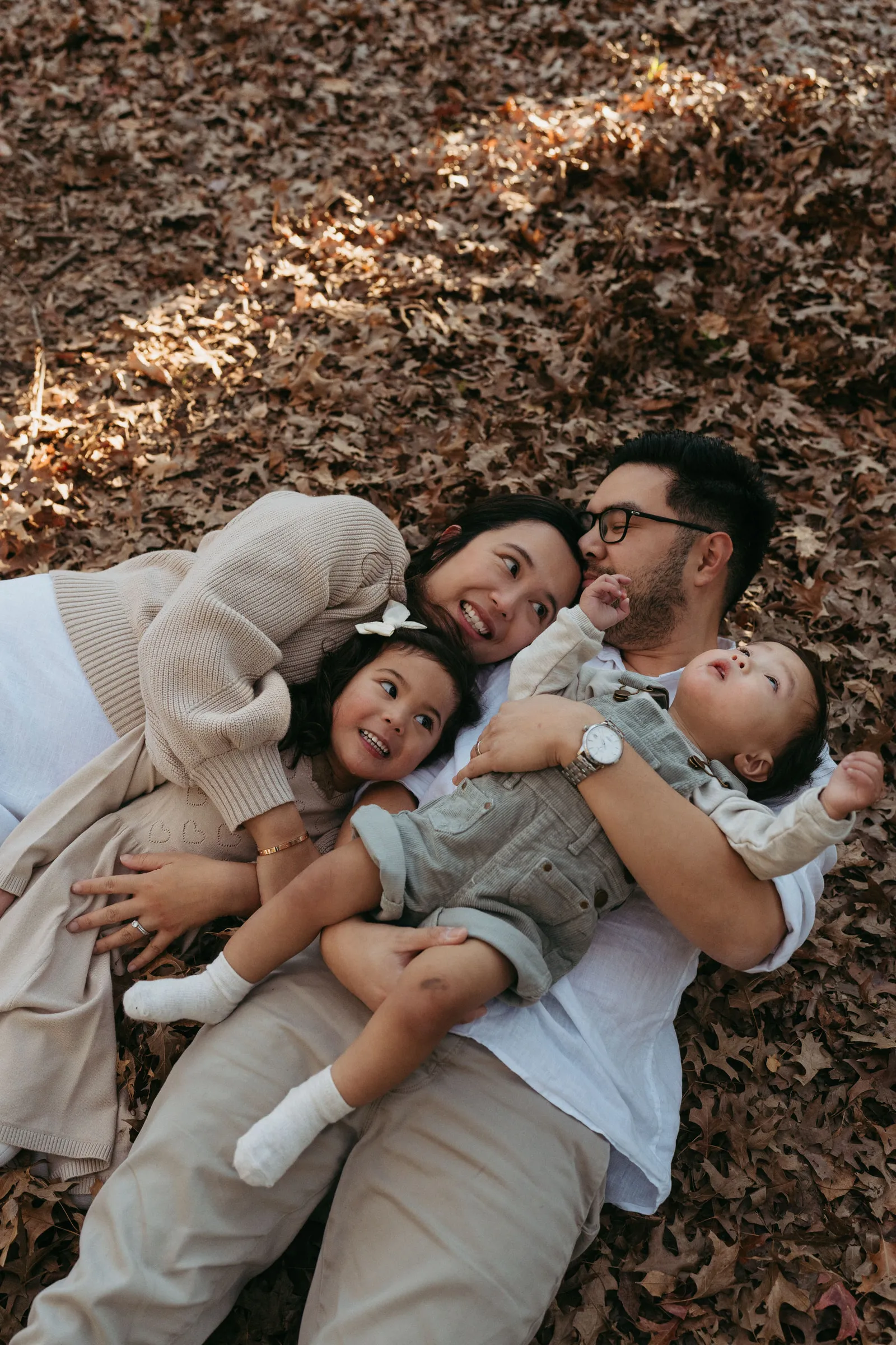 A family lying together in a pile of autumn leaves, giggling