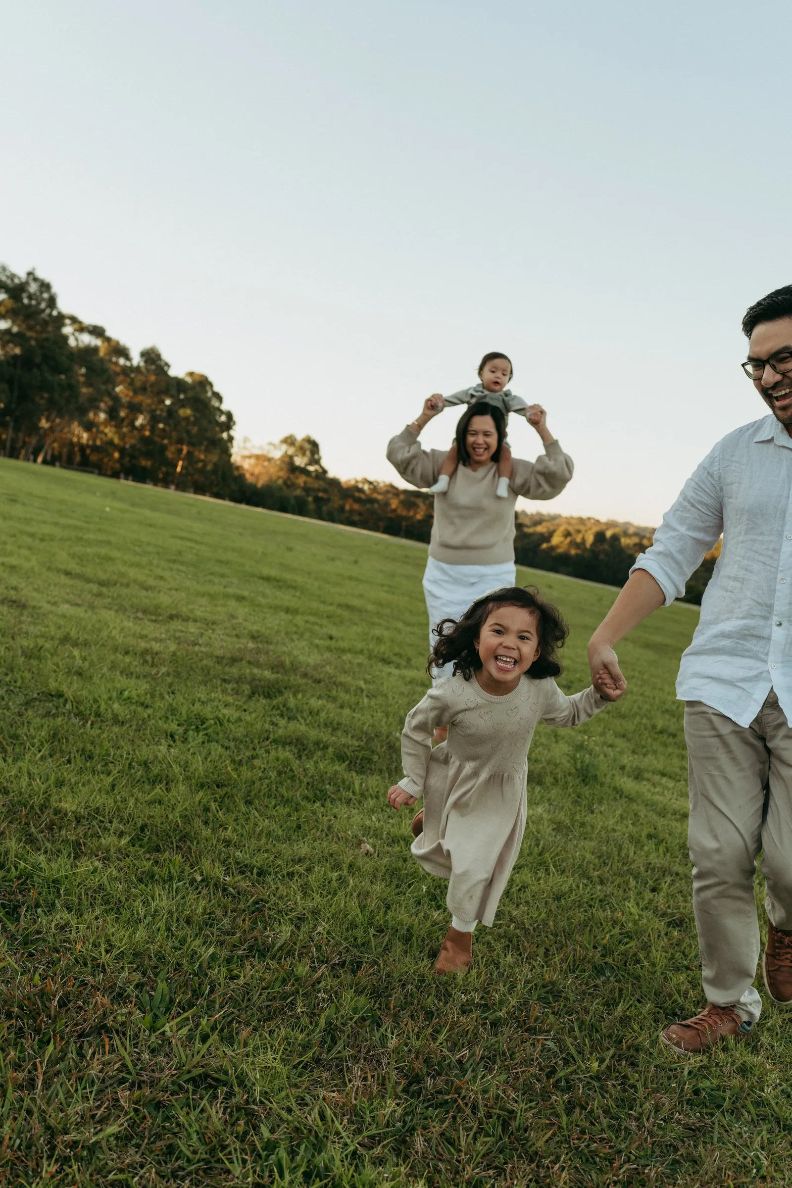 A little girl running across the grass holding dad’s hand