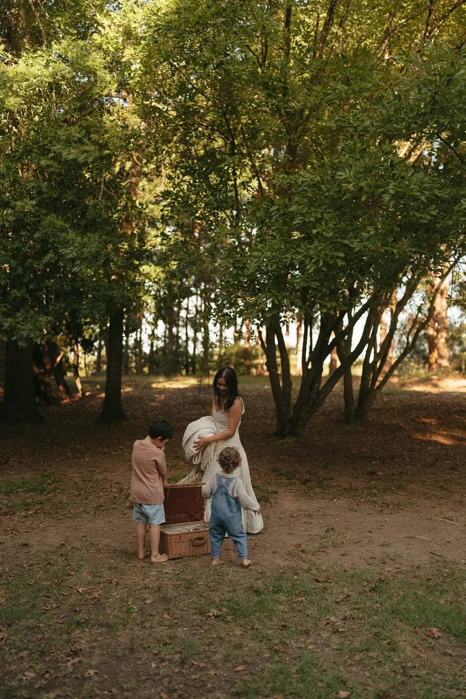 A mum and her children beneath tall trees