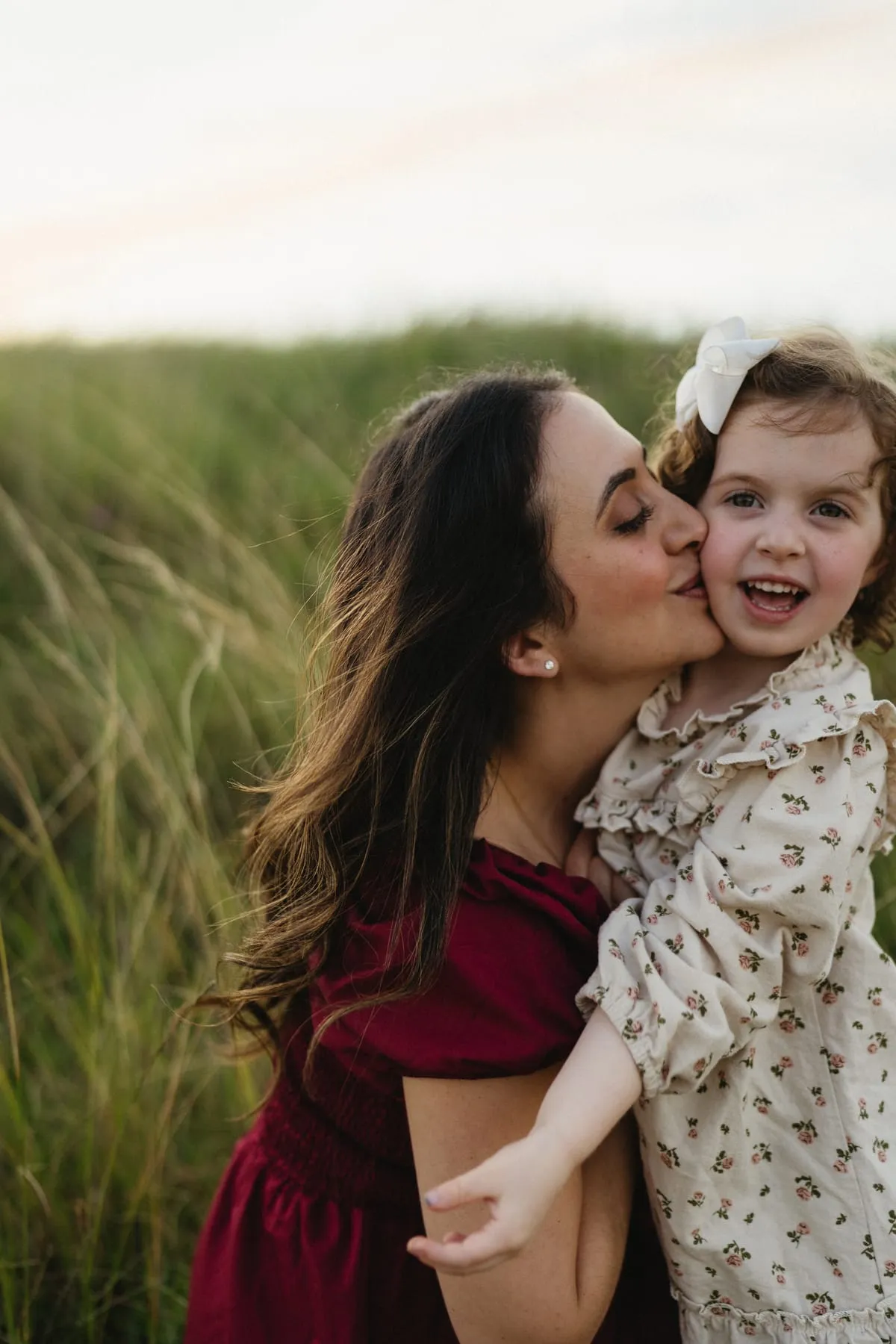 A mum kissing her daughter’s cheek in the dunes
