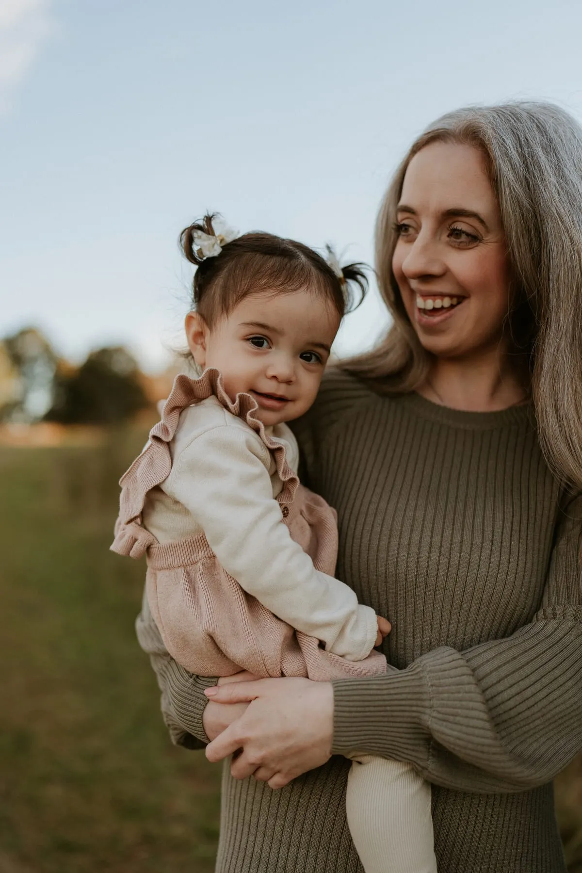 A toddler in pigtails on a laughing woman’s hip