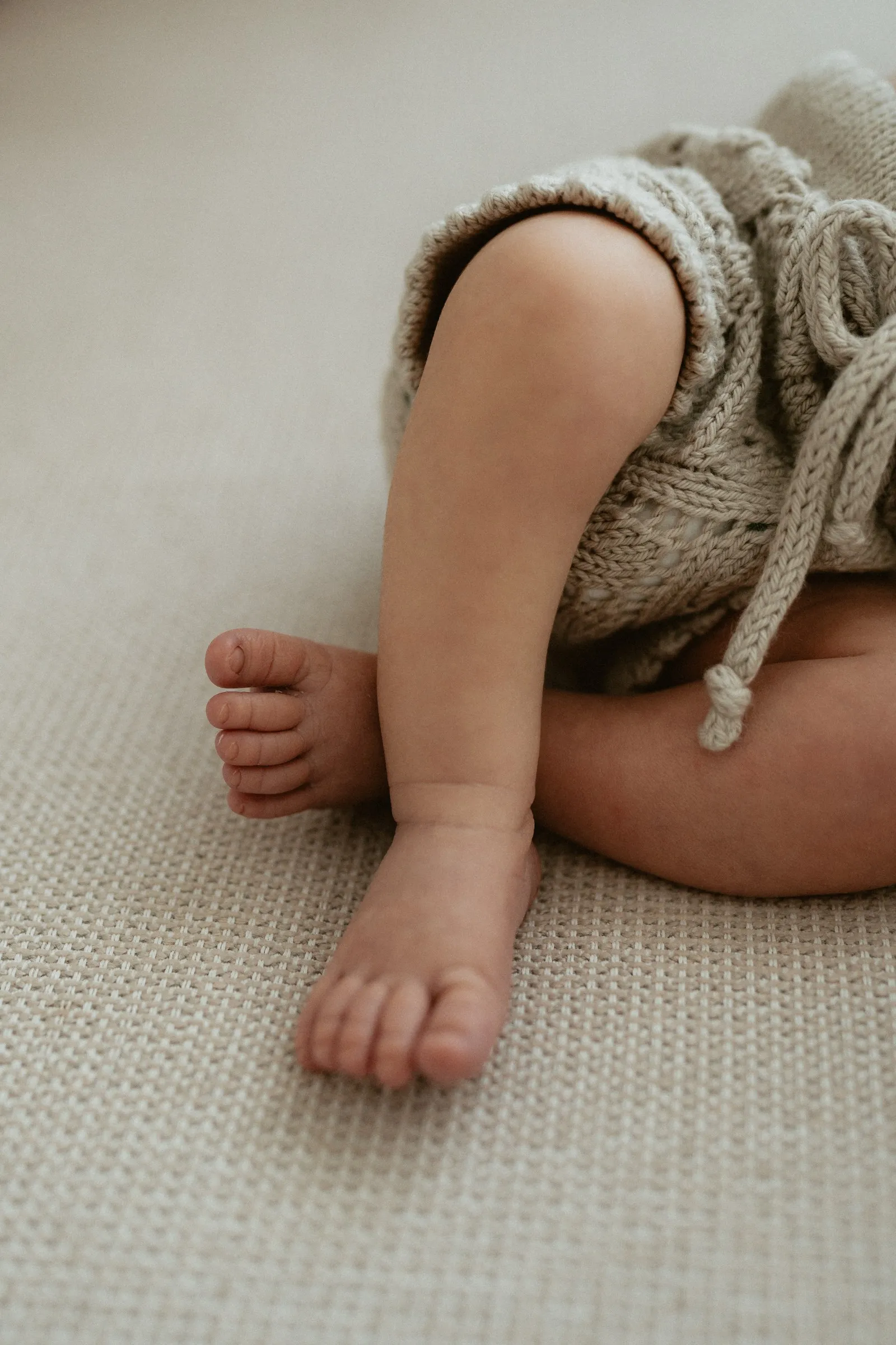 A newborn’s tiny feet tucked against a knitted outfit