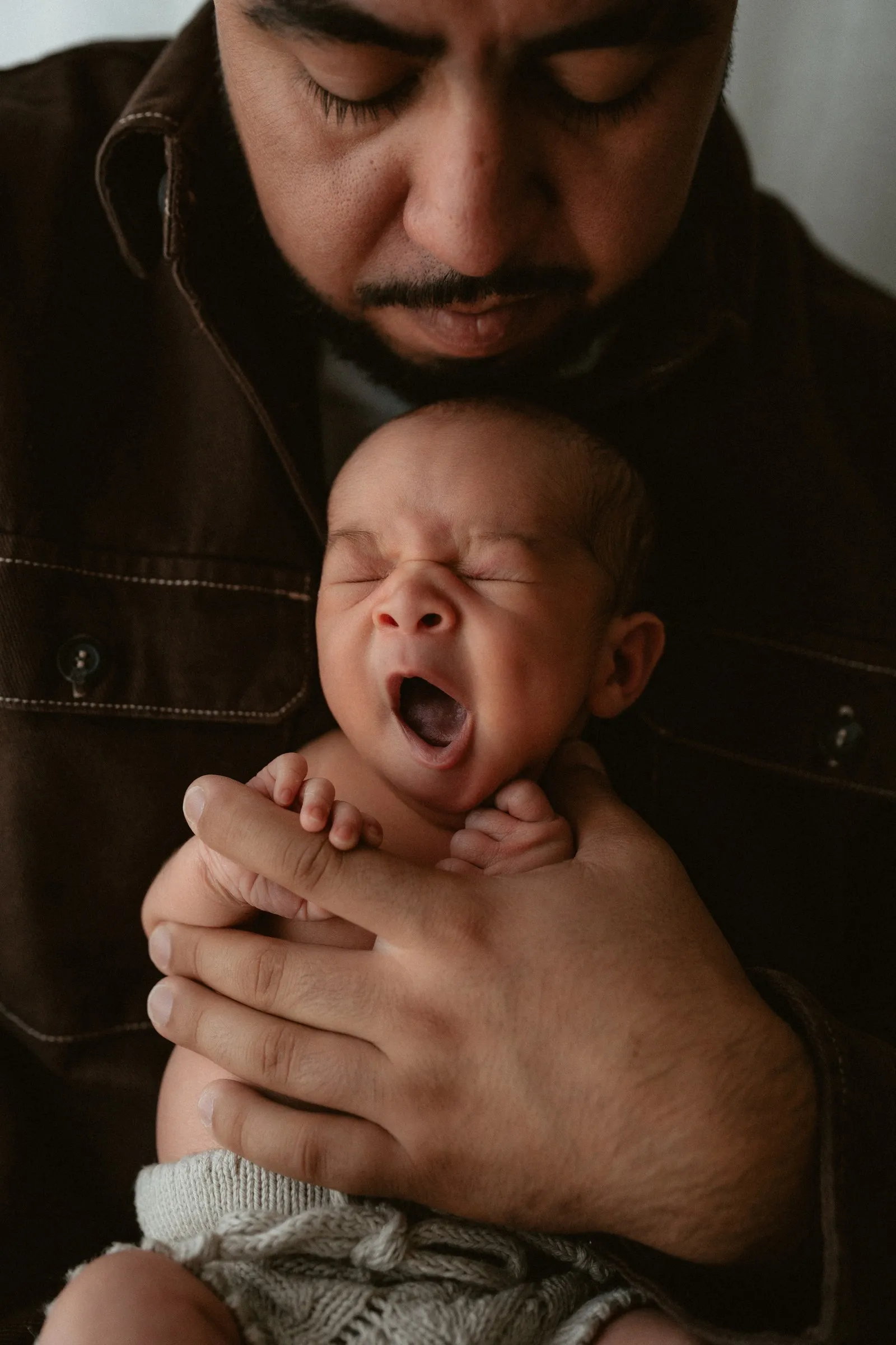 A newborn yawning in dad’s hands