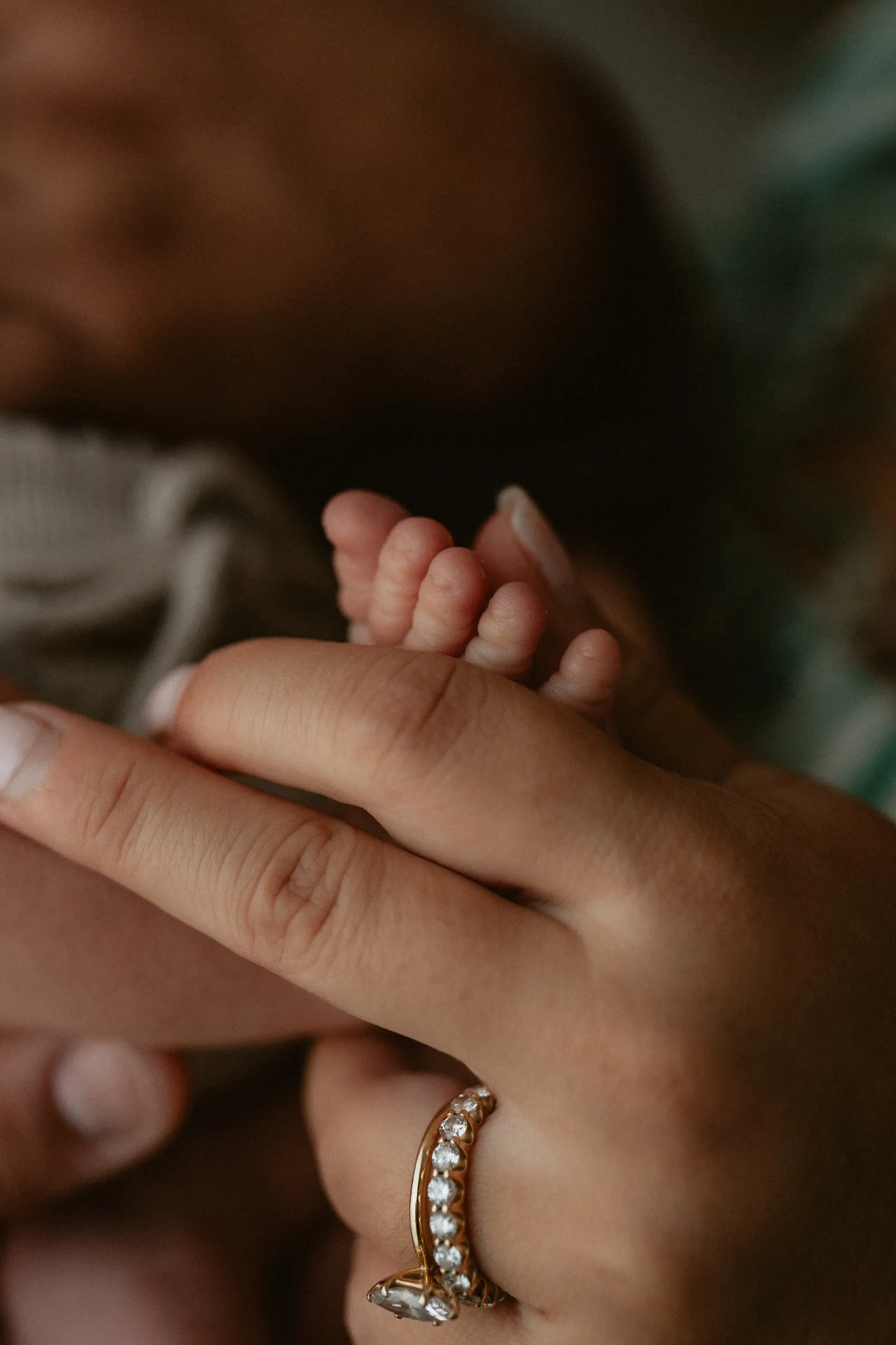 A newborn’s fingers curled around a parent’s finger