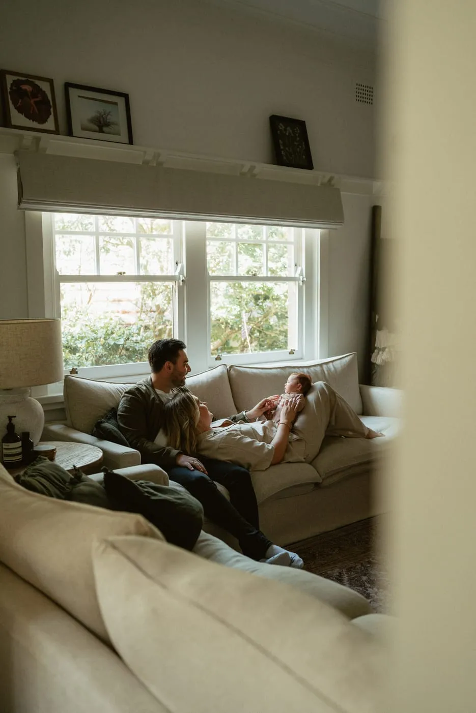 A young family resting together on the couch with their newborn