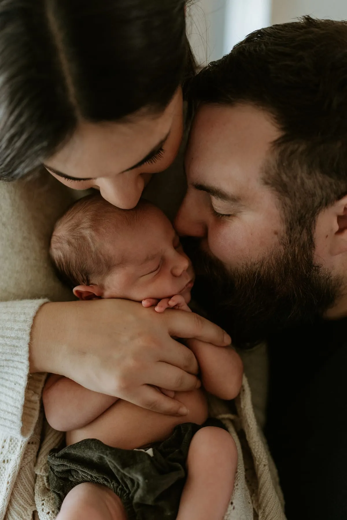 Parents kissing their newborn’s head